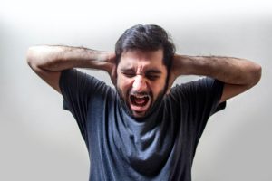 man holding ears in anger
